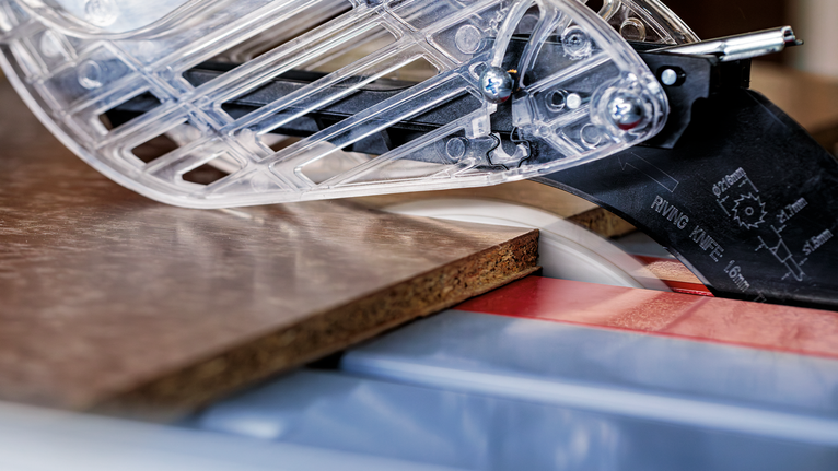 작업장에서 원형 톱으로 나무판을 자르고 있습니다.