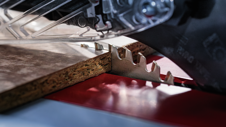 원형 톱으로 파티클보드 조각을 자르는 모습.