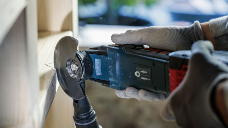 안전 장비를 착용하고 전동공구를 사용하여 나무를 자르는 사람.