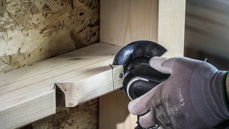 PRO ACZ 100 BB 멀티커터 날, 100mm 안전 장비를 착용한 사람이 각도 그라인더로 나무 들보를 자릅니다.