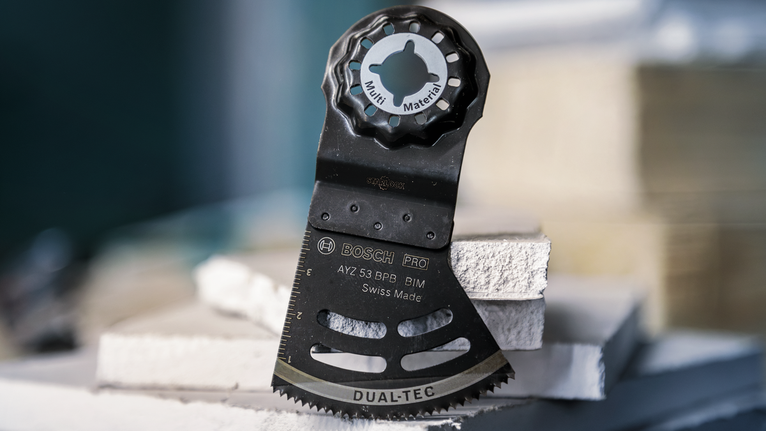 PRO AYZ 53 BPB 멀티커터 날, 53 x 40mm 쌓아 올린 건축 패널 위에 수직으로 놓인 진동식 멀티툴 블레이드입니다.