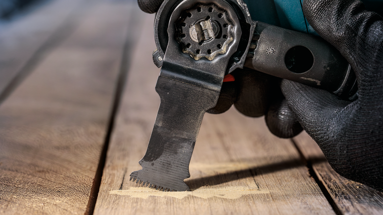 안전 장비를 착용하고 멀티툴을 사용해 나무를 자르는 사람입니다.