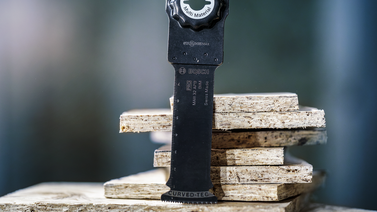 쌓인 파티클보드 위에 진동 톱날이 놓여 있습니다.