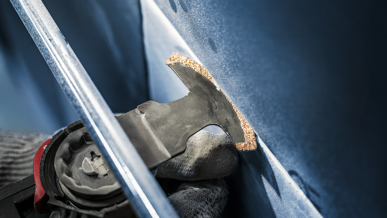 PRO MATI 68 RT3 멀티커터 날, 2.8 x 68mm 안전 장비를 착용한 사람이 진동 도구를 사용하여 패널을 자릅니다.