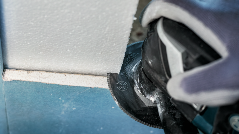 PRO ACZ 100 SWB 멀티커터 날, 100mm 안전 장비를 착용한 사람이 전동 공구로 석고보드를 자릅니다.