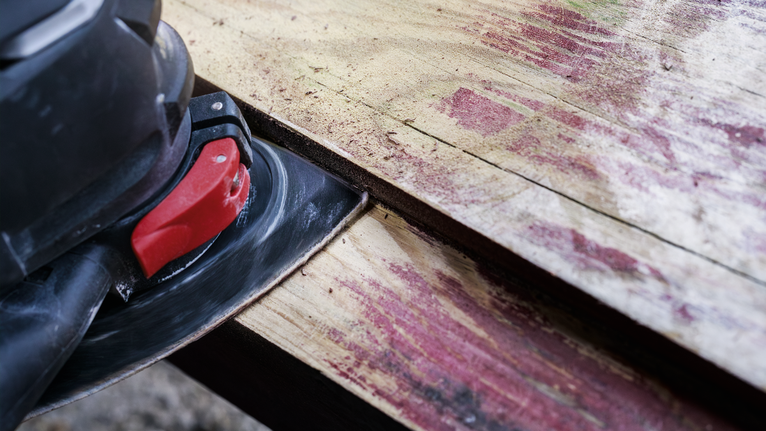 전기 샌더로 낡은 나무 판자를 매끄럽게 다듬는 모습입니다.