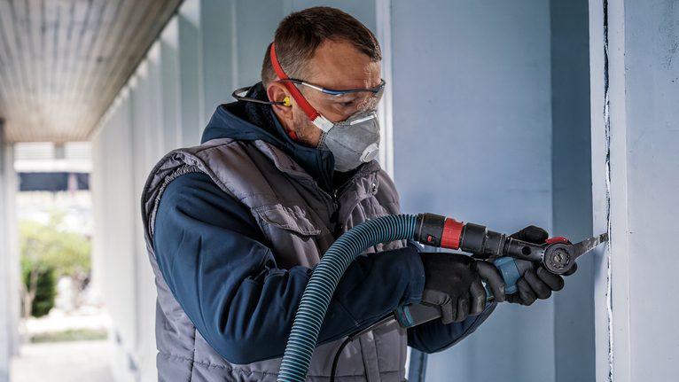 PRO MAII 32 SLC 멀티커터 날, 32 x 70mm 안전 장비를 착용한 사람이 전동 공구로 벽을 자릅니다.