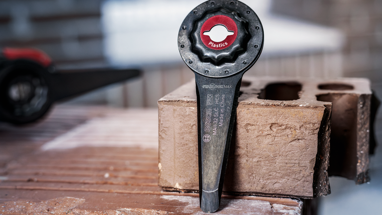 PRO MAII 32 SLC 멀티커터 날, 32 x 70mm 콘크리트 블록 위에 올려놓은 플라스틱 절단용 진동 도구 부속품입니다.