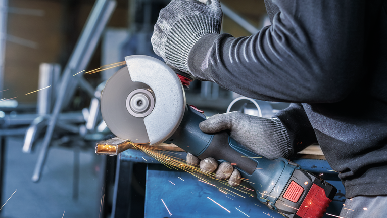 안전 장비를 착용한 사람이 금속을 갈아서 불꽃이 난다.