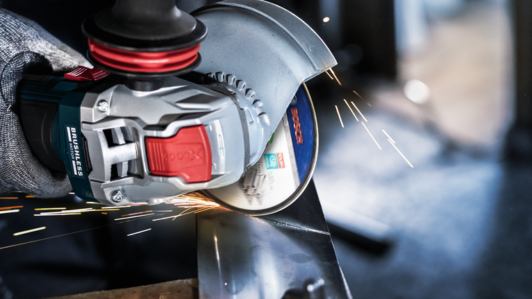 안전장비를 착용한 사람이 금속을 갈아서 밝은 불꽃을 낸다.