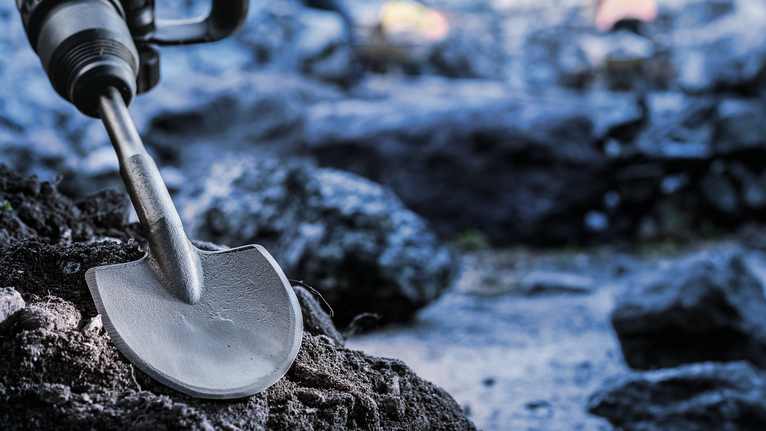 삽 끌이 달린 회전 망치가 바위 땅을 뚫고 나갑니다.