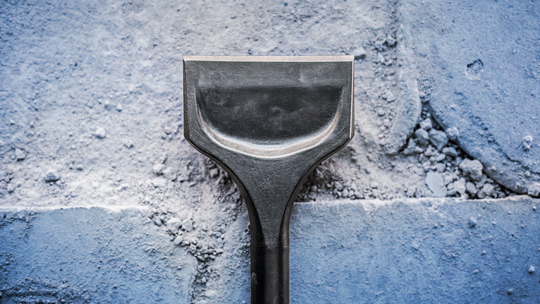 넓은 끌날로 석조 벽에서 석고를 제거합니다.