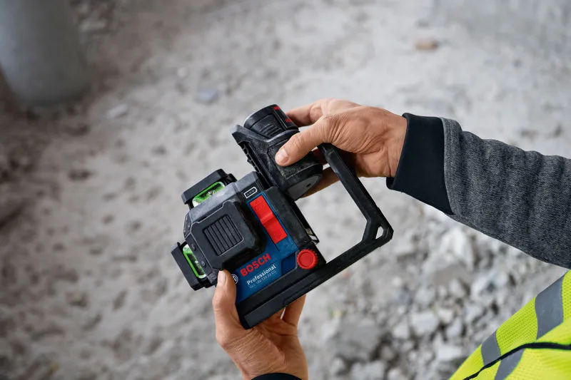 안전 장비를 착용한 사람이 배터리가 부착된 레이저 레벨링 도구를 들고 있습니다.