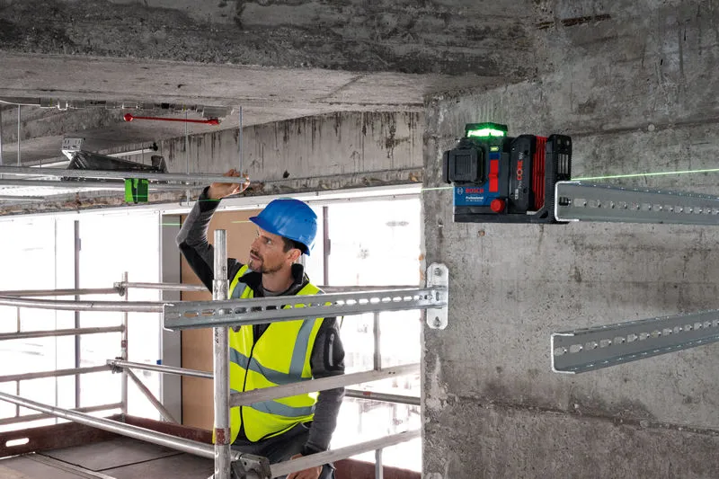 안전 장비를 착용한 사람이 레이저 레벨링 도구를 사용하여 금속 막대를 정렬하고 있습니다.