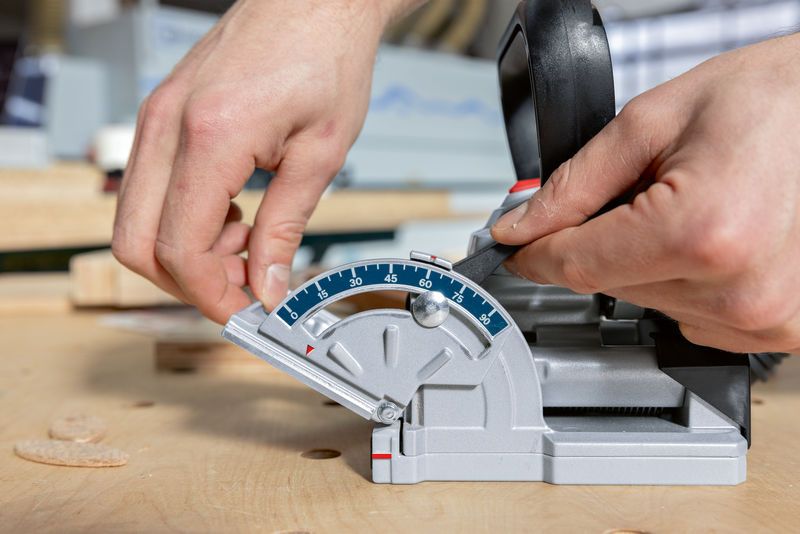 나무 작업대 위에 놓인 비스킷 조이너의 각도를 조정하는 사람.