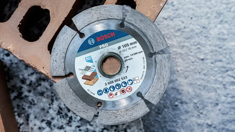 벽돌과 콘크리트를 자르기 위한 분할된 다이아몬드 블레이드가 건축용 블록 위에 놓여 있습니다.