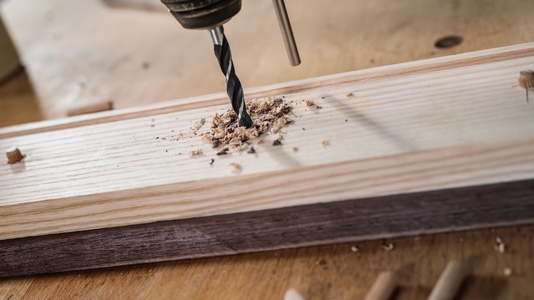 드릴로 나무판에 구멍을 뚫고, 비트 주위에 나무 조각을 붙입니다.