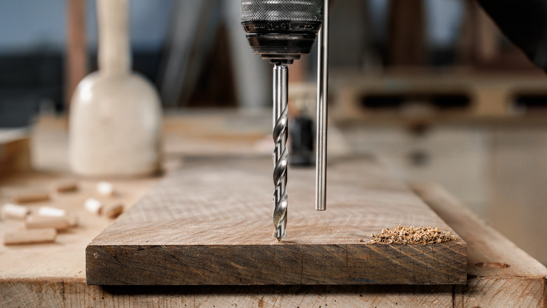 작업대 위의 나무판에 구멍을 뚫는 드릴입니다.