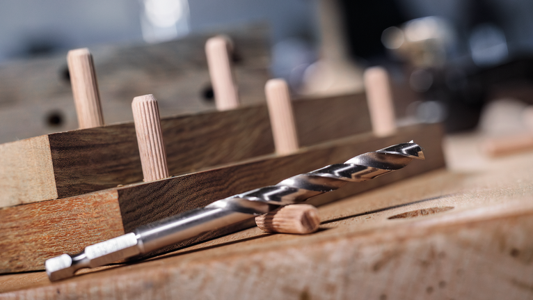 목공 작업대에 놓인 드릴 비트와 나무 막대.