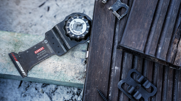 야외의 나무 판자 위에 놓인 진동하는 멀티툴 칼날.