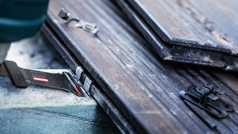 진동하는 멀티툴이 근처의 라미네이트 바닥, 나사, 클립을 절단합니다.