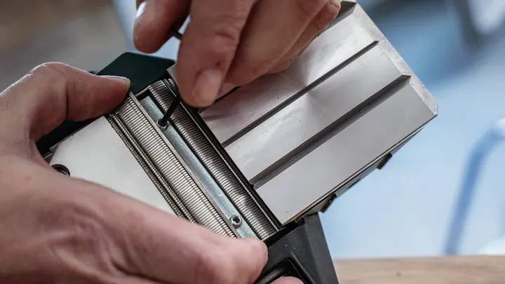 사람이 육각 렌치를 사용하여 금속 도구 부품을 조정합니다.