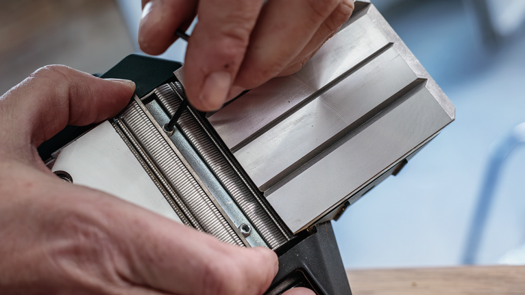 사람이 육각 렌치를 사용하여 금속 도구 부품을 조정합니다.