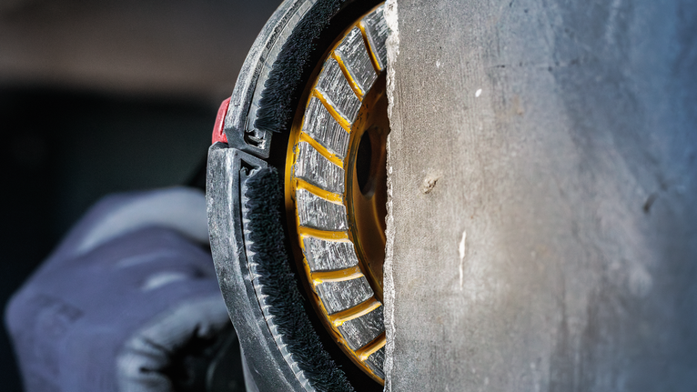 안전 장비를 착용한 사람이 다이아몬드 칼날을 사용해 콘크리트를 자릅니다.