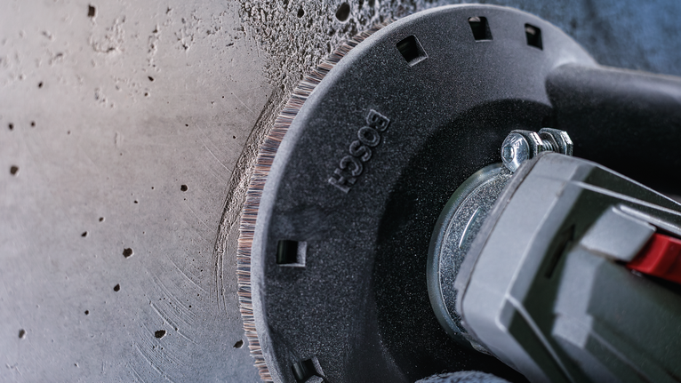 각도 분쇄기로 콘크리트 벽을 절단하고 있는데, 가장자리에 먼지가 보입니다.