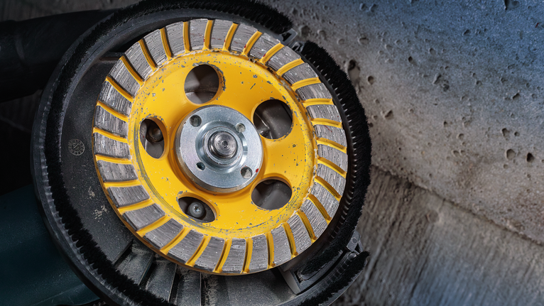 다이아몬드 컵 휠 그라인더로 거친 콘크리트 표면을 매끄럽게 다듬습니다.