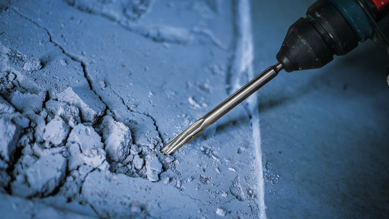 회전 해머로 콘크리트 표면을 부수고 있습니다.