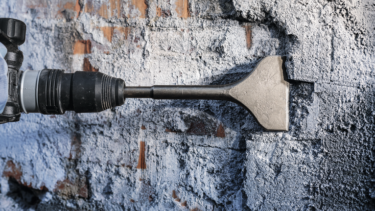 철거 과정에서 끌 망치로 콘크리트 벽을 부수는 모습입니다.