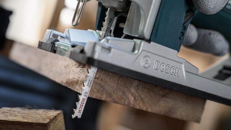 안전 장비를 착용한 사람이 퍼즐을 사용하여 나무판을 자르고 있습니다.