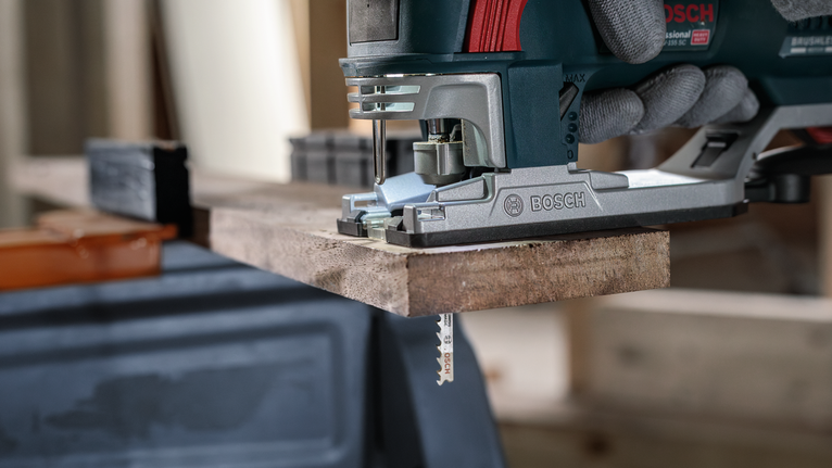 안전 장비를 착용한 사람이 퍼즐을 사용하여 나무판을 자르고 있습니다.