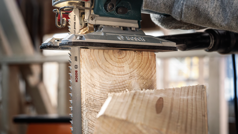 안전 장비를 착용한 사람이 퍼즐을 사용하여 나무 들보를 자릅니다.