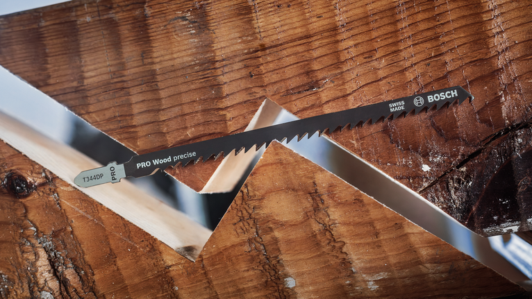 각진 절단면을 가진 두 개의 맞물린 나무 조각 사이에 톱날을 놓습니다.
