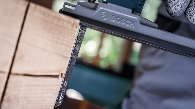 안전 장비를 착용한 사람이 왕복톱을 사용하여 나무를 자릅니다.