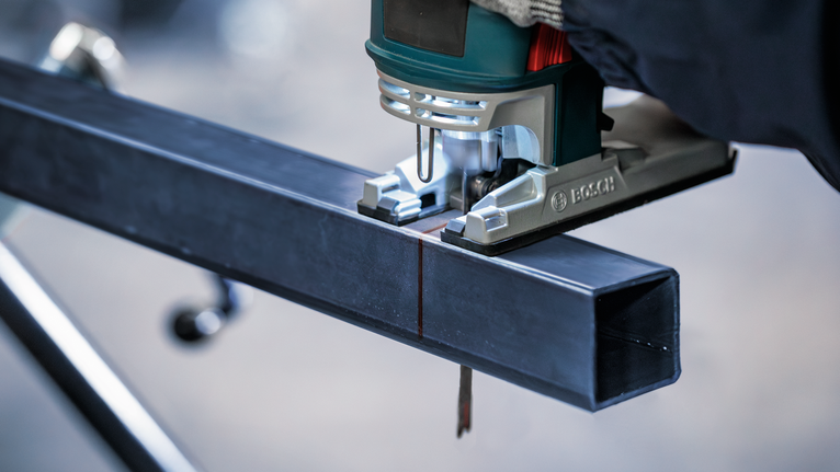 PRO Metal Pipes and Profiles T321AF 직쏘날, 132mm, 5개 안전 장비를 착용한 사람이 퍼즐을 사용하여 금속 막대를 자릅니다.