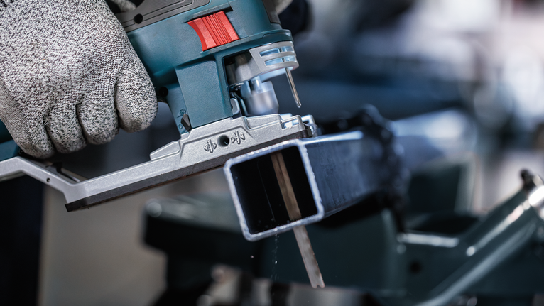 PRO Metal Pipes and Profiles T321AF 직쏘날, 132mm, 5개 안전 장비를 착용한 사람이 퍼즐을 사용하여 금속 막대를 자릅니다.