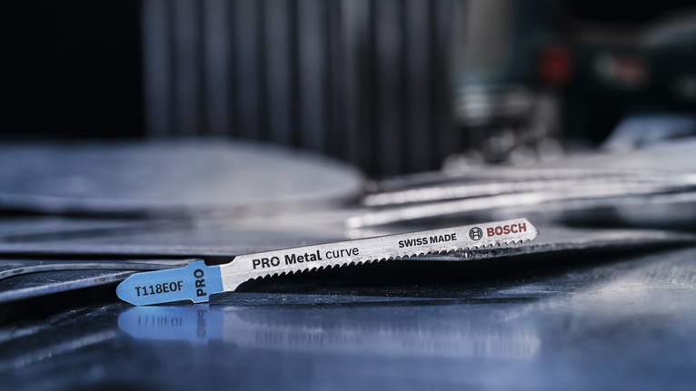 PRO Metal curve T118EOF 직쏘날, 83mm, 5개 작업장에 쌓인 금속판 위에 금속 톱날을 올려놓은 모습입니다.