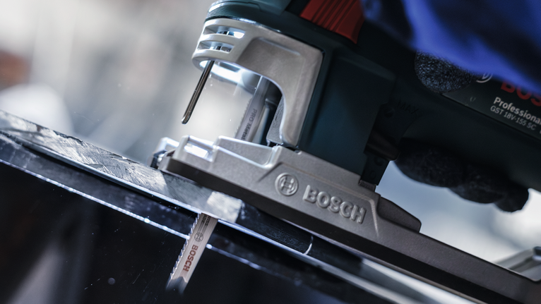 PRO Metal thick and thin T123XF 직쏘날, 100mm, 5개 안전 장비를 착용한 사람이 퍼즐을 사용해 검은색 금속판을 자르고 있습니다.