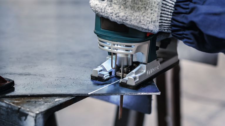 PRO Metal thick and thin T123XF 직쏘날, 100mm, 5개 안전장비를 착용한 사람이 퍼즐톱으로 금속판을 자르고 있습니다.