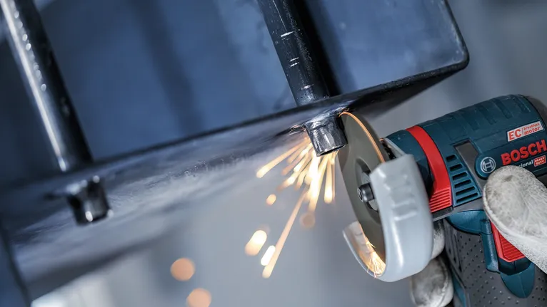 안전 장비를 착용한 사람이 금속 막대를 갈아서 불꽃을 낸다.