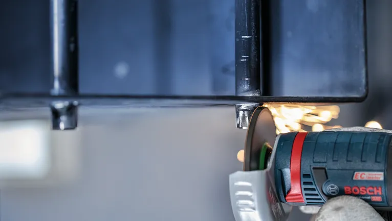 안전 장비를 착용한 사람이 금속을 갈아서 불꽃이 난다.