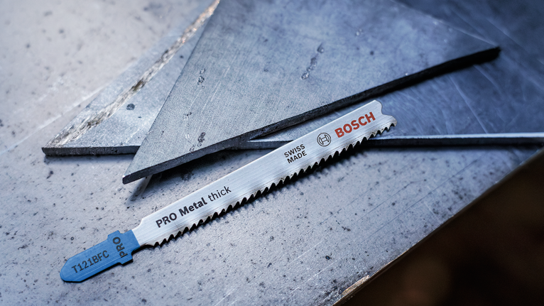 잘린 금속판 옆의 강철 표면에 금속 톱날을 올려놓은 모습입니다.