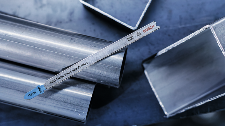 반짝이는 금속 파이프와 사각 튜브 위에 금속 톱날이 놓여 있습니다.