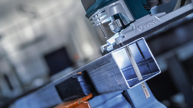 작업장에서 전동공구가 금속 빔을 절단하고 있습니다.