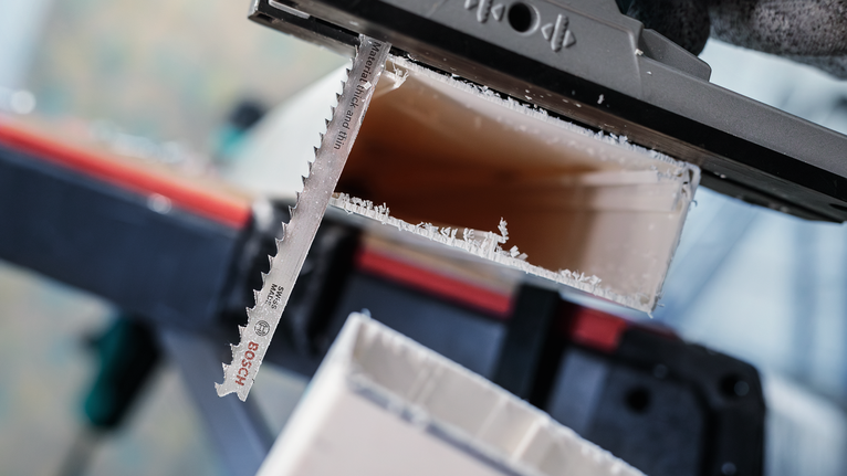 안전장비를 착용한 사람이 톱날로 플라스틱 파이프를 자릅니다.