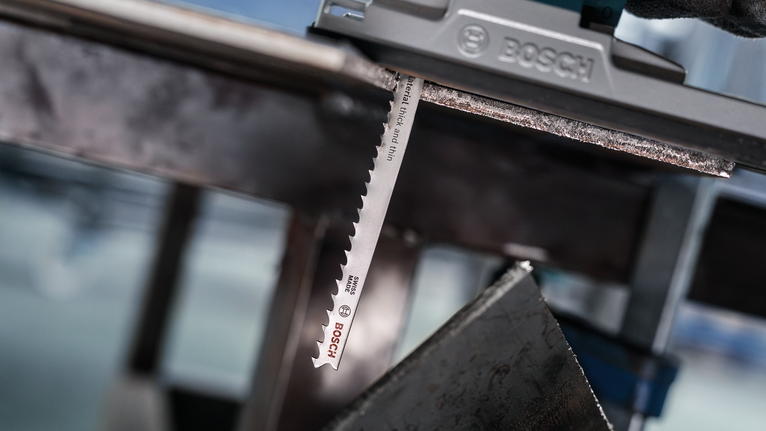 안전 장비를 착용한 사람이 퍼즐을 사용해 금속판을 자릅니다.