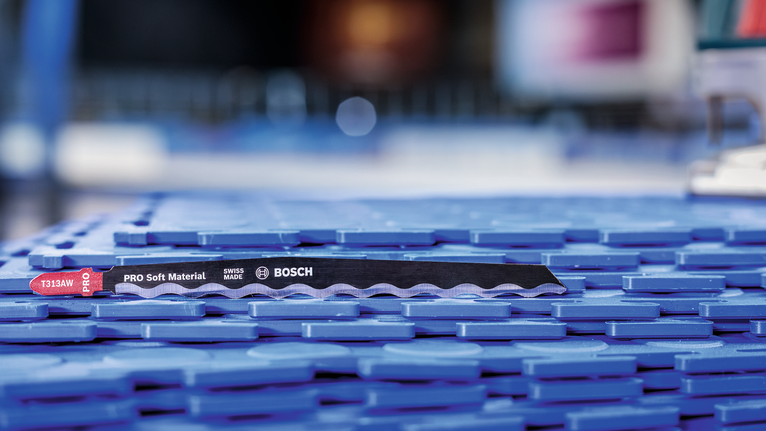 파란색 플라스틱 표면에 부드러운 재료를 자르는 톱날을 올려놓았습니다.